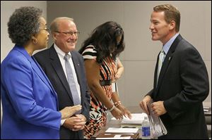 Lucas County Board of Election members Brenda Hill, left, and Peter Handwork, center, greet Secretary of State Jon Husted right, before opening a special meeting on Tuesday.