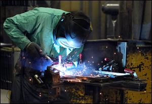 A worker welds a chair together during the tour of MTS Seating.