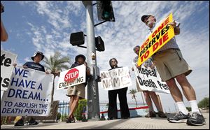 John Zemblidge, right, of Phoenix, leads a group of about a dozen death penalty opponents in prayer as the protest the possible execution of Joseph Rudolph Wood at the state prison in Florence, Ariz.