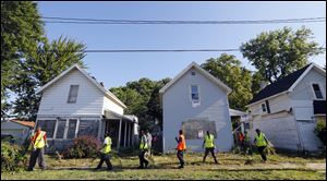 Members of Pathway, teenagers and young adults employed through a Lucas County summer job placement program, mow and clean debris from abandoned homes on Earl St. near Kingston Ave.  during a clean-up of the East Toledo neighborhood.