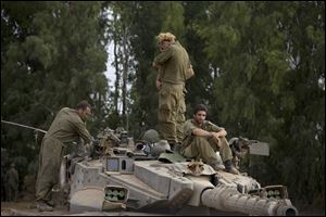 Israeli soldiers work on a tank near the Israel and Gaza border today as tanks and warplanes bombarded the Gaza Strip. Hamas militants stuck to their demand for the lifting of an Israeli and Egyptian blockade in the face of U.S. efforts to reach a cease-fire. 