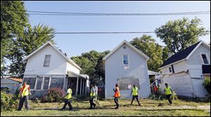 Members of Pathway mow and clean debris from homes on Earl Street near Kingston Avenue.