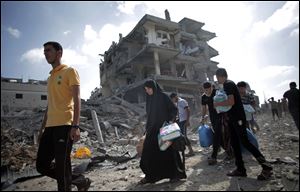 Palestinians pass by destroyed houses after they salvage usable things in their belongings found at their destroyed houses during a 12-hour cease-fire in Gaza City's Shijaiyah neighborhood, Saturday, July 26, 2014. 