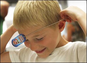 ‘‍Math wizard’ William Hanthorn, 6, puts his dog tag on after earning the title for his work in the summer math club.