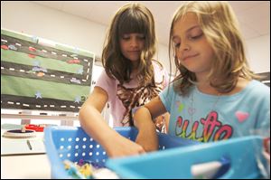 Maci Karrick, 10, left, and Natalie Karrick, 7, pick out prizes during the summer math club at Coy Elementary School in Oregon. The two girls selected from prizes Tuesday that included candy, bracelets, and dog tags, purchased with money donated by Coy’‍s parents association.