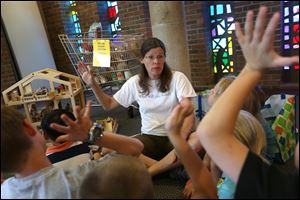 Susan Rowland Miller, associate executive director for the Maumee Valley Habitat for Humanity, leads a story about sharing during Vacation Bible School on Wednesday at Sylvania United Church of Christ.
