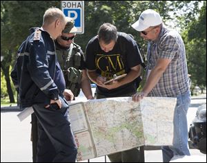 Ukrainian Ministry Emergency officer, left, Donetsk People's Republic fighter, 2nd left, and members of the OSCE mission in Ukraine examine a map as they discuss the situation around the site of the crashed Malaysia Airlines Flight 17 in the city of Donetsk, eastern Ukraine Sunday.