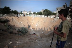 Palestinian check a crater caused by an Israeli strike at a cemetery in the Jabaliya refugee camp, northern Gaza Strip, today.