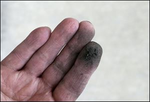 Joe Cook, an activist with the Virginia chapter of the Sierra Club, displays a substance that he scraped from a windowsill in homeowner Timothy Taylor's house in Norfolk, Va. Cook and Taylor's mother, Catherine, believe the substance is coal dust emitted from freight trains running behind the home to Norfolk Southern's nearby Lamberts Point coal terminal.