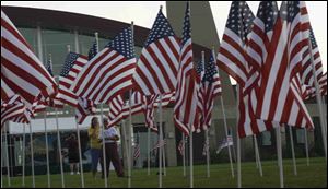 People walk through flag display at Owens Community College in Findlay. Community members from Toledo to Findlay are reaching out to help heal the wounds caused by recent destruction of American flags along North Main Street here.