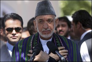 Afghanistan's President Hamid Karzai, center, talks to the media representatives after Eid al-Fitr prayer at the presidential palace in Kabul, Afghanistan.