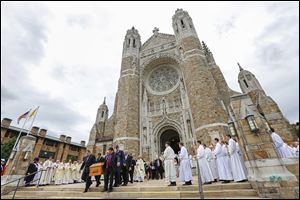 Pallbearers carry the casket of Auxiliary Bishop Robert Donnelly from Our Lady, Queen of the Most Holy Rosary Cathedral as clergy members  sing after his funeral.