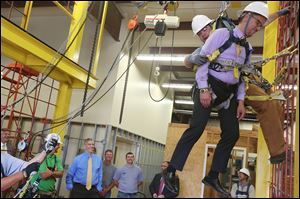 Arne Duncan, left, laughs as he watches Thomas Perez  be ‘‍rescued’ by student Tim Thebeau of Swanton during a tour of the training facility in Rossford.