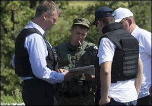 Alexander Hug, deputy head of the OSCE mission to Ukraine, left, his colleagues and a pro-Russian rebel, 2nd left, examine a map as they try to estimate security conditions outside the city of Donetsk, eastern Ukraine Wednesday.