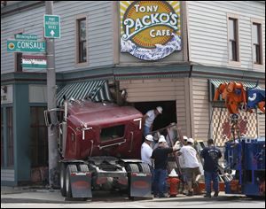 Workers remove a window from Tony Packo's Cafe on Front Street in East Toledo, Friday, August 1, 2014, before removing the tractor of a semi truck that crashed into it earlier in the day. The trailer had already been removed.