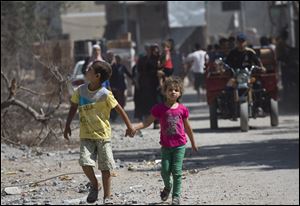Palestinian children walk hand in hand as residents return to the heavily bombed Gaza City neighborhood of Shijaiyah today.