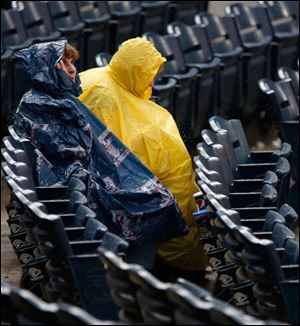 Michigan residents Kathy Burke, left, and her sister Nancy Burke wear plastic rain gear to shield themselves from the weather during a brief rain delay Thursday  night.