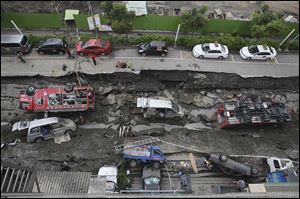 Vehicles are left lie in a destroyed street following multiple explosions from an underground gas leak in Kaohsiung, Taiwan early today.