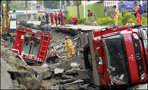 Rescue workers use a sniffer dog to look for missing persons believed to be buried as firetrucks lie damaged after massive gas explosions in Kaohsiung.