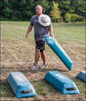 Start head coach Tyson Harder puts agility bags in place for football practice at Start High School in Toledo on Friday.