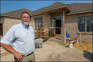 Chuck Barchick, front, stands in front of 7514 Pinafore Lane in Maumee as Sean Mowery works on the Barchick Custom home. Mr. Barchick, also head of the Home Builders Association of Greater Toledo, says his company has four homes under construction.