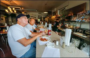 Brothers Butch, left, and Denny Varnes of Toledo watch news coverage of the water crisis as they grab a bite to eat at My House Diner.
