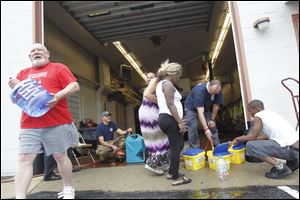 Firefighters and citizens work to fill containers with water at the fire station at 1102 S. Wheeling St. in Oregon.