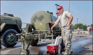 Staff Sgt. Josh Reiss, left, and Staff Sgt. Brock Mowry of the 200th Red Horse Engineers fill a cooler from a ‘‍water buffalo’ with water purified by the Air Force. 