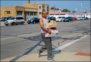 Melvin Newton of Toledo carries cases he received at the water distribution center sponsored by the Cherry Street Mission.