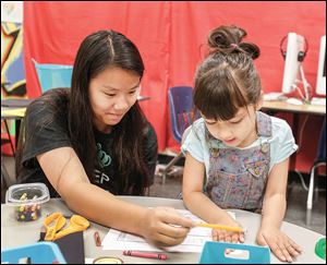Teacher’s aide Kelly Rudolph of Toledo, left, tutors kindergarten student Roxy Ostertag on Thursday.  The Little Jackets Academic Camp in Perrysburg is for students who need or want extra help in the summer.