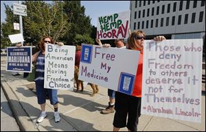 Linda Turvey, left, Eddie Currier, back, center, and wife Heather Currier, of Northwest Ohio NORML, demonstrate outside One Government Center in Toledo today. The group presented petitions to Toledo City Council proposing an ordinance for the decriminalization of marijuana. 