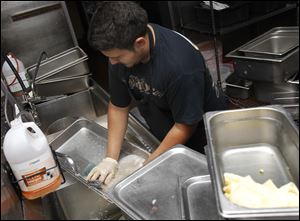 Antonio Vasquez cleans dishes in the kitchen of El Vaquero at The Docks.
