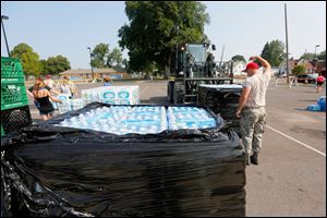 Staff Sgt. Josh Reiss of the 200th Red Horse Engineers, directs a pallet of water to a storing area in the parking lot of Woodward High School to be distributed on Sunday.