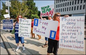 Linda Turvey, left, Eddie Currier, back center, and Mr. Currier’s wife, Heather Currier, of Northwest Ohio NORML, demonstrate outside One Government Center in Toledo. They passed out petitions Monday proposing an ordinance for the decriminalization of marijuana.