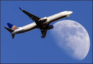 A United Airlines jet approaching Los Angeles International Airport passes in front of a Waxing Gibbous moon on July 17.