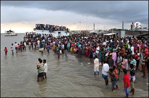 People gather on the banks of  the River Padma after a passenger ferry carrying hundreds of people capsized in Munshiganj district, Bangladesh, Monday. 