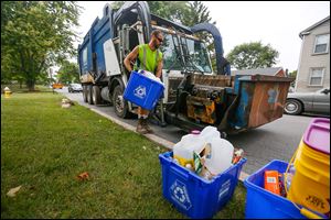 Bryan Shipman, with Republic Services, empties a recycling bin on West Broadway in Maumee.