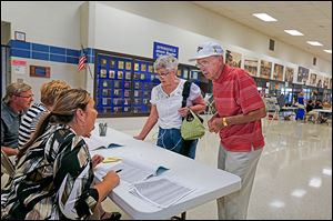 Precinct 5 voters Dorothy, left, and Frank Konwinski sign in to vote at Springfield High School with poll workers, from  left, Paul and Lynne Philibin of Monclova Township and Linda Kulwicki of Toledo.