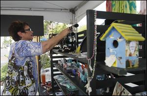 A shopper admires jewelry created by the Toledo School for the Arts students at last year’s Levis Commons Fine Art Fair in Perrysburg.