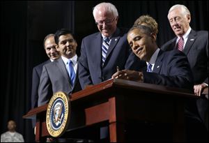President Barack Obama, flanked by Senate Veterans Affairs Committee Chairman Sen. Bernie Sanders, I-Vt., left, and House Minority Whip Steny Hoyer of Md., right, signs H.R. 3230, the Veterans’ Access to Care through Choice, Accountability, and Transparency Act of 2014 today at the Wallace Theater in Fort Belvoir, Va. 
