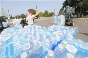 Staff Sgt. Josh Reiss, of the 200th Red Horse Engineers, directs a pallet of water to a storing area in the parking lot of Woodward High School to be distributed this past Sunday during the 'do not drink' water advisory.
