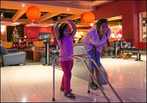 Jacqueline Martinez and her daughter Isabel, 4, watch the progress of a ball down the lane at Lucky Strike in Chicago. While 69 million Americans still bowl at least once a year, league play has made a dramatic decline.