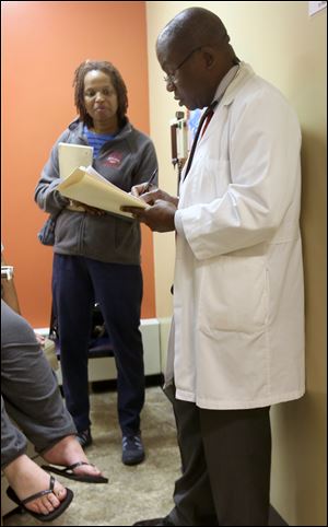 Nurse practitioner student Linda Joyce and Dr. Bonaventure Okoro consult with a patient at That Neighborhood Free Health Clinic in North Toledo.