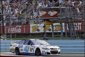 AJ Allmendinger takes the checkered flag to win a NASCAR Sprint Cup Series auto race at Watkins Glen International on Sunday in Watkins Glen N.Y.