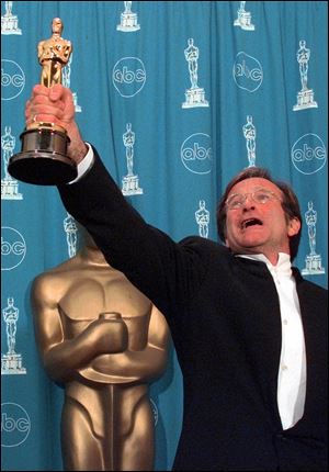 Robin Williams holds his Oscar high backstage at the 70th Academy Awards at the Shrine Auditorium in Los Angeles Monday, March 23, 1998. Williams won Best Supporting Actor for 
