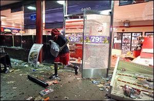 A man leaves a store after a looting Sunday in Ferguson, Mo. 