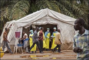Health workers, center rear, screen people for the deadly Ebola virus before entering the Kenema Government Hospital.