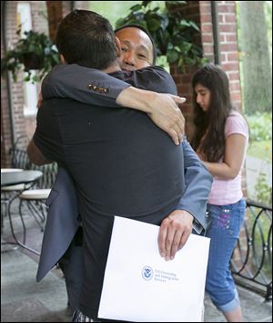 Lydio Delicana Dema-Ala of Defiance, formerly of the Philippines, gets a hug from his friend Joseph Littleton of Toledo after becoming an American citizen during the ceremony.