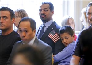 Taleb Al Zakwani, 8, hugs his father,  Mohamed Said Al Zakwani, formerly of Oman, during a naturalization ceremony at the Manor House in Wildwood Preserve Metropark on Monday.