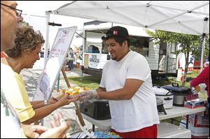 Juan Viveros, a cook with El Sabor Mexicano, center, hands a plate of food to a customer during last year's Mexican-American Festival.